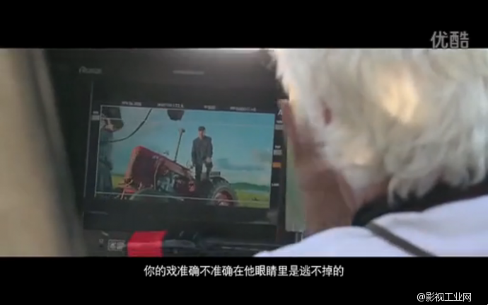 过肩镜头拍摄阿诺导演专注地看着监视器画面.